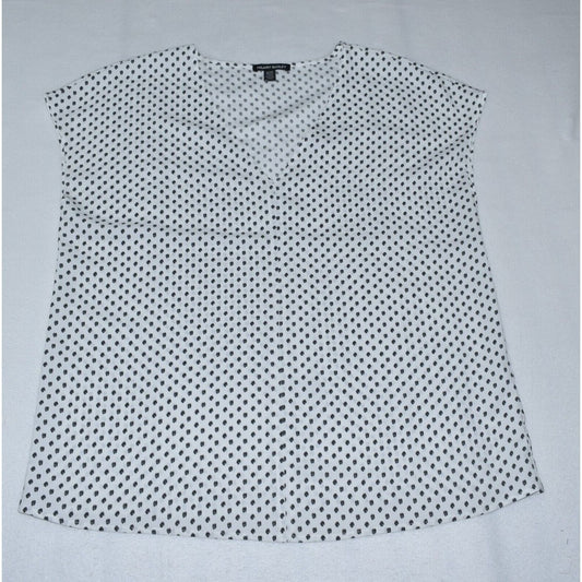 A sleeveless white blouse with a small black polka dot pattern, laid flat on a light gray background.
