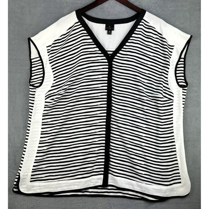 A sleeveless knit vest with a black and white horizontal stripe pattern, black trim, and a V-neckline, hanging on a dark wooden hanger against a gray background.