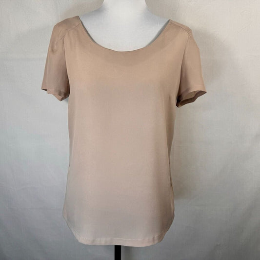 A short-sleeve scoop-neck blouse in a light beige or taupe color, displayed on a white mannequin torso against a light gray fabric backdrop.
