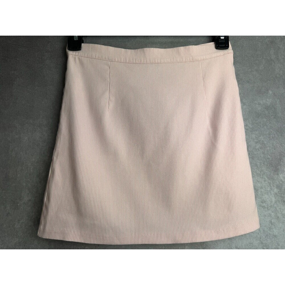 A light pink ribbed mini skirt with an A-line silhouette, hanging on black hangers against a textured gray background.