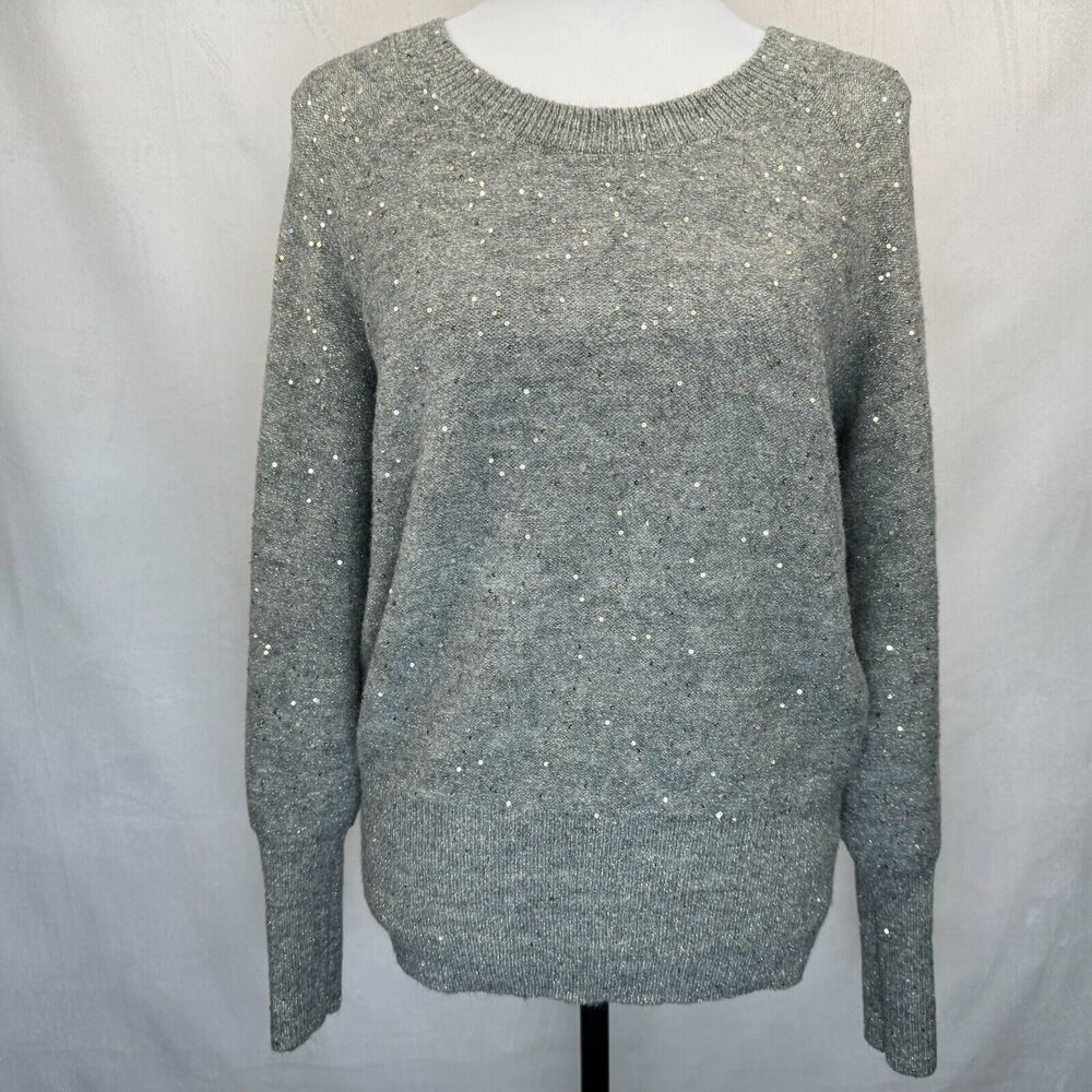 A gray knit sweater with subtle silver sequin embellishments, displayed on a white mannequin torso against a light gray fabric backdrop.