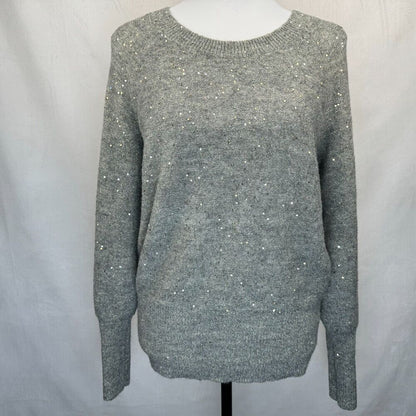 A gray knit sweater with subtle silver sequin embellishments, displayed on a white mannequin torso against a light gray fabric backdrop.