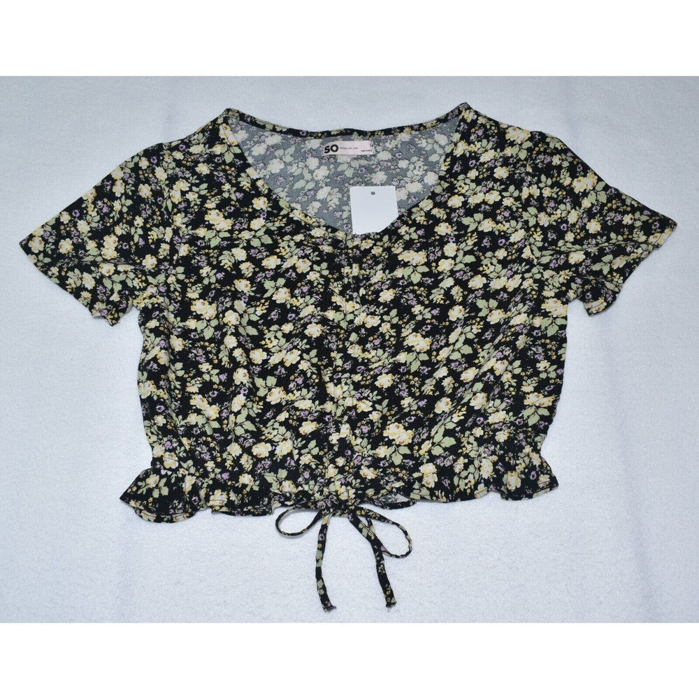 A short-sleeve crop top with a black and beige floral pattern, featuring a V-neckline, front tie detail, and a white price tag attached.