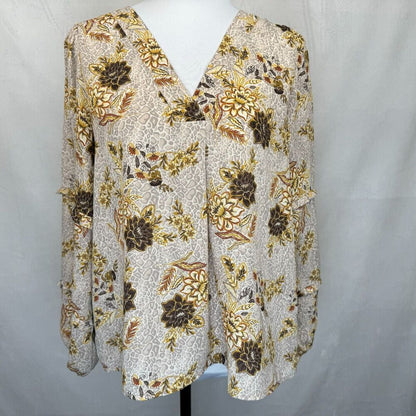 A women's long-sleeve blouse with a V-neckline, displayed on a white mannequin torso. The blouse features an all-over abstract floral pattern in brown, gold, and beige tones on a light cream background.