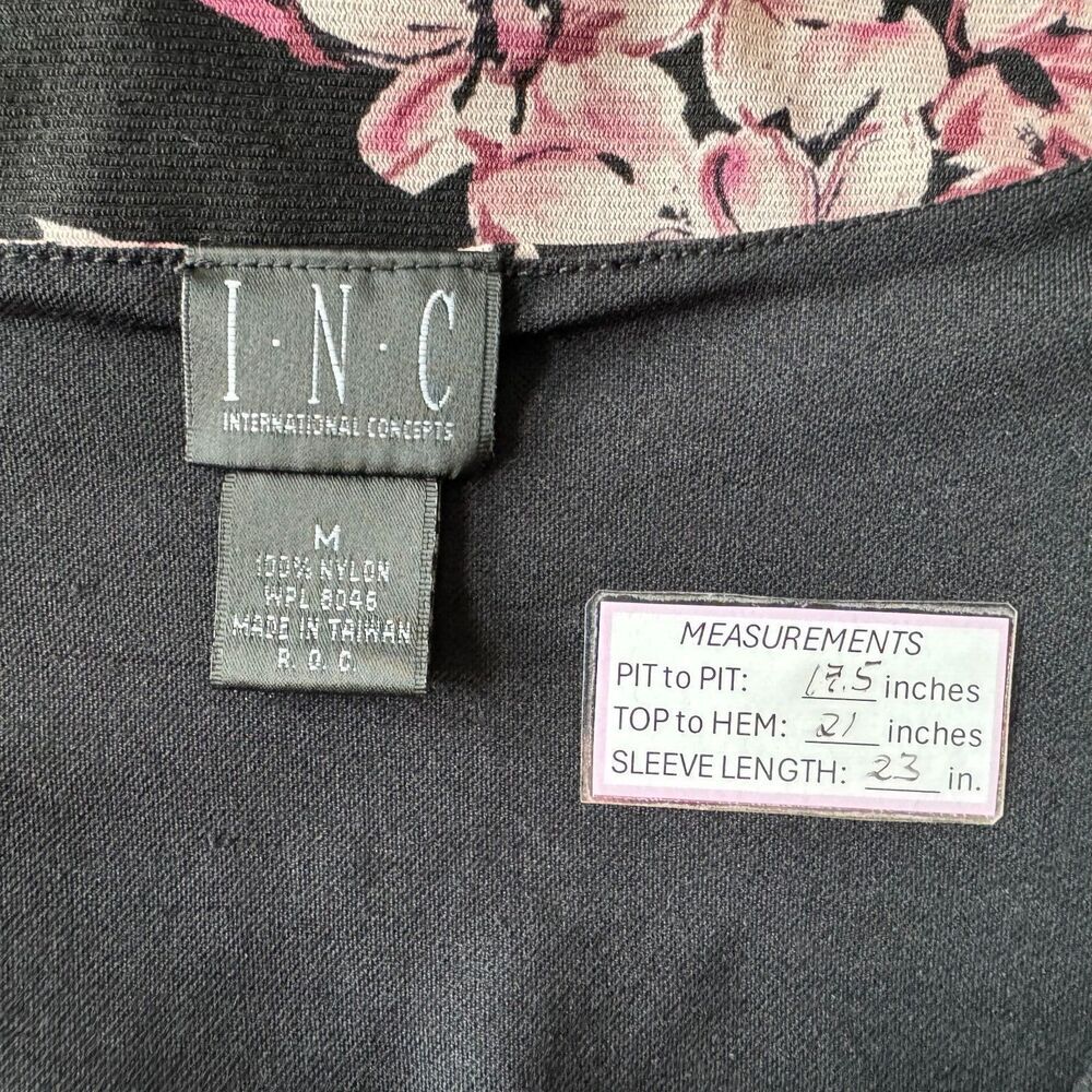 Close-up of a garment's inner neck area showing a floral print neckline, a dark gray brand label reading I.N.