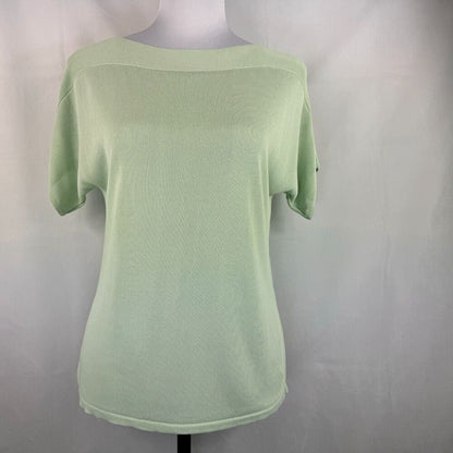 A light sage green short-sleeve knit top displayed on a mannequin torso against a light gray fabric backdrop.