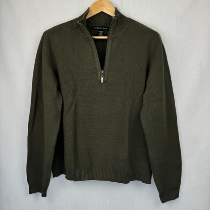 An olive green quarter-zip knit sweater hanging on a wooden hanger against a light gray textured wall.