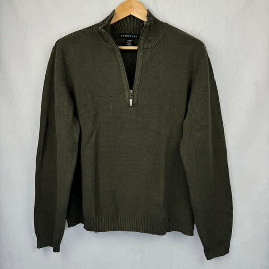 An olive green quarter-zip knit sweater hanging on a wooden hanger against a light gray textured wall.
