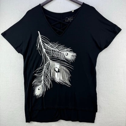 A black short-sleeve V-neck top with a lace-up detail at the neckline and a large white feather graphic on the front, hanging on a dark hanger against a light textured wall.