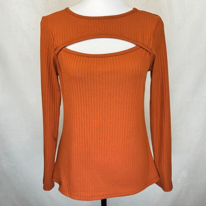 An orange ribbed knit long-sleeve top with a scoop neck and a horizontal cutout across the chest, displayed on a white mannequin torso against a light gray fabric backdrop.