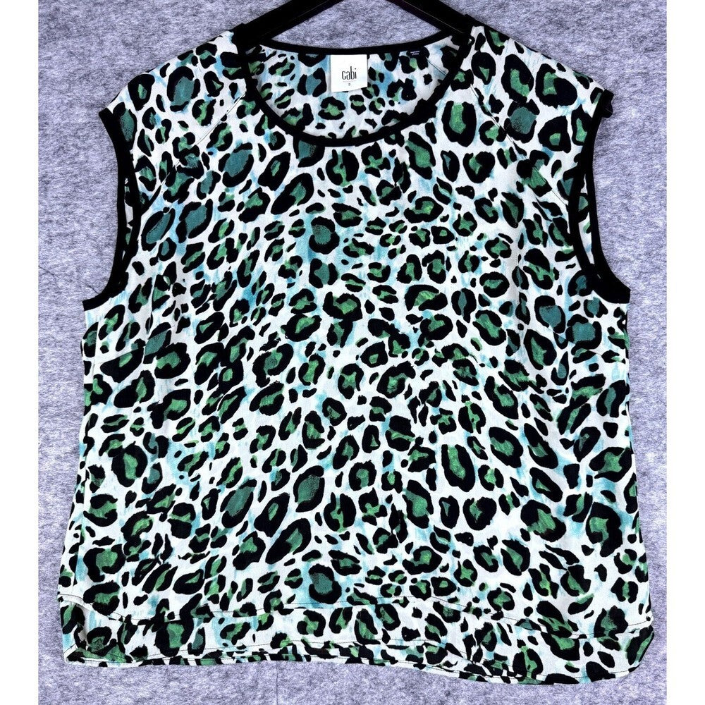 A sleeveless crop top with a green, black, and white leopard print pattern, laid flat on a gray textured background.