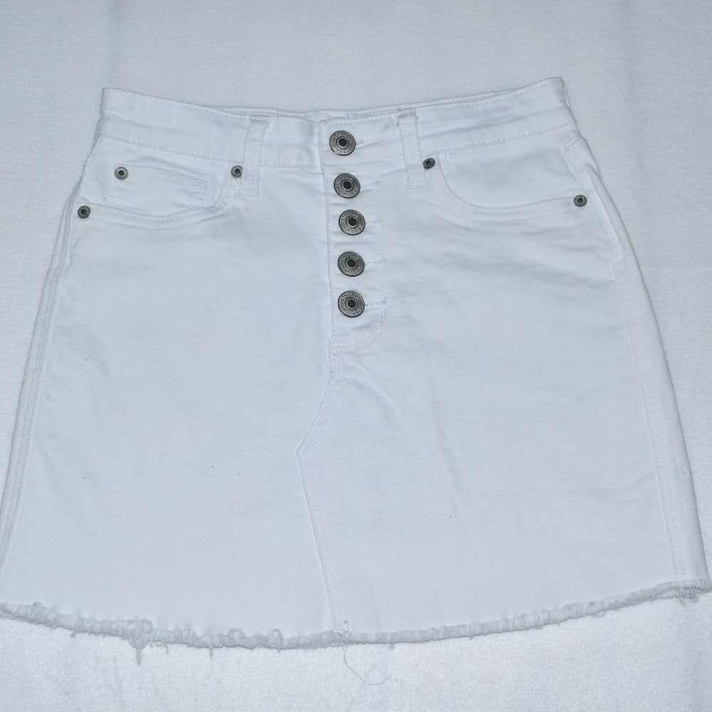 White denim mini skirt with a high waist, five prominent silver-tone front buttons, and a raw frayed hem.