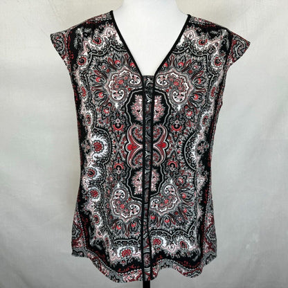 A sleeveless V-neck blouse with a black, white, and red paisley pattern, displayed on a white mannequin torso against a light gray fabric backdrop.