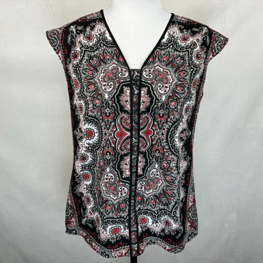 A sleeveless V-neck blouse with a black, white, and red paisley pattern, displayed on a white mannequin torso against a light gray fabric backdrop.