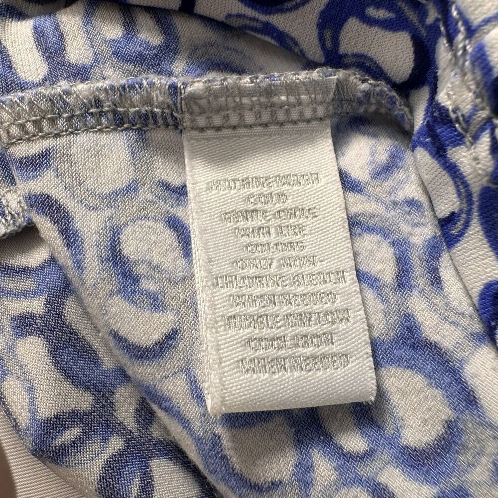 Close-up of a garment's interior neck label and patterned lining. The white woven label reads 'SILKERWEAR' and 'COLD WASH', while the surrounding fabric features a blue and white abstract scroll pattern.