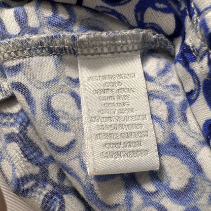 Close-up of a garment's interior neck label and patterned lining. The white woven label reads 'SILKERWEAR' and 'COLD WASH', while the surrounding fabric features a blue and white abstract scroll pattern.