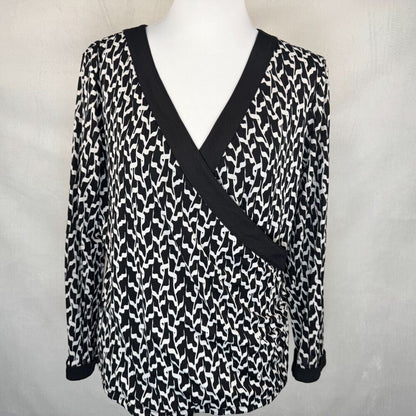 A black and white patterned long-sleeve wrap top displayed on a white mannequin torso against a light gray fabric backdrop.