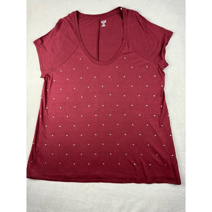 A women's short-sleeve scoop neck top in burgundy, decorated with a grid pattern of small white rhinestones, laid flat on a light beige fabric background.