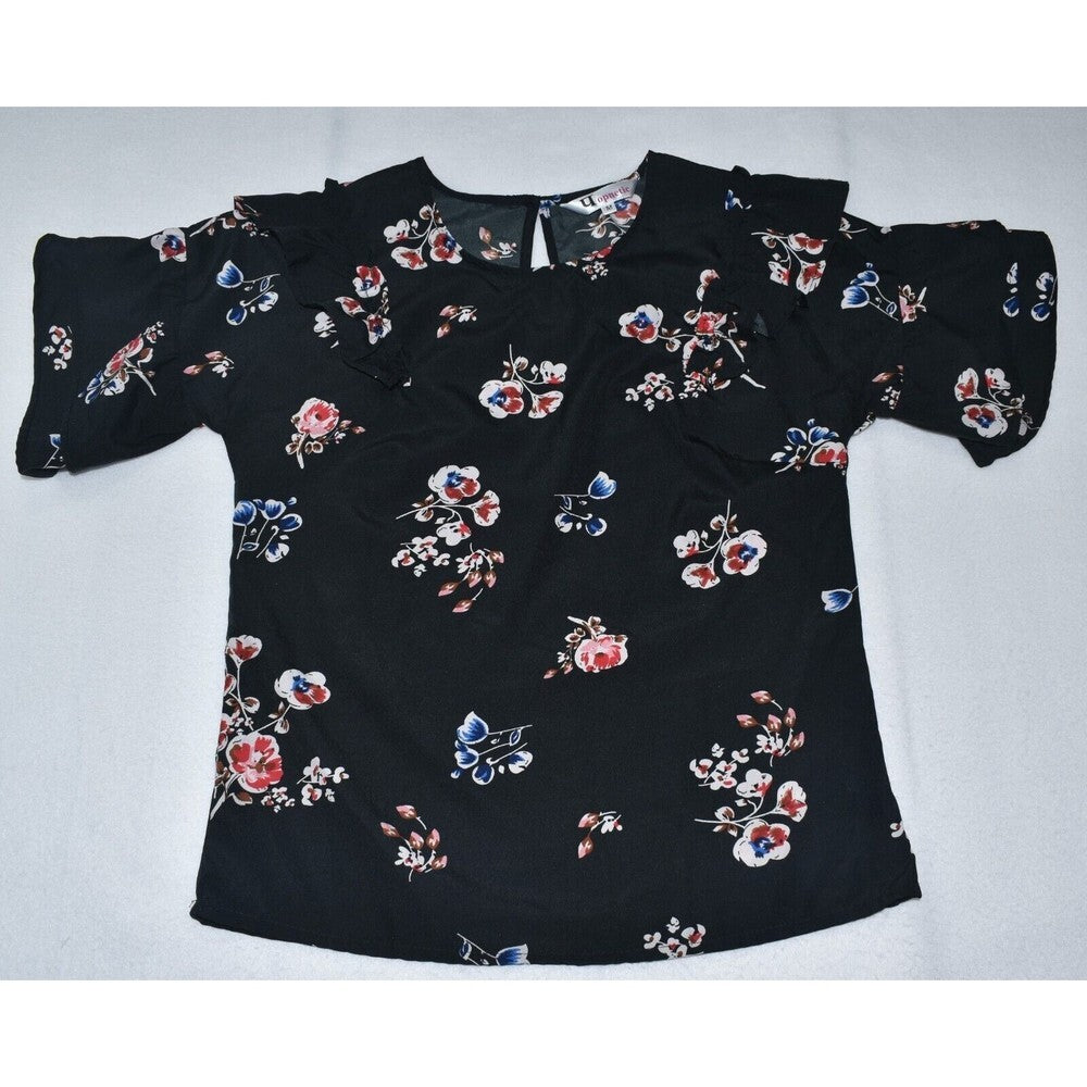 A black short-sleeve blouse with a colorful floral and butterfly print, laid flat on a light gray background.