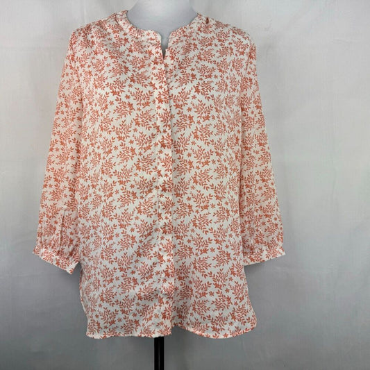 A long-sleeve blouse with a dense orange floral and leaf print on an off-white base, displayed on a mannequin torso against a light gray fabric backdrop.