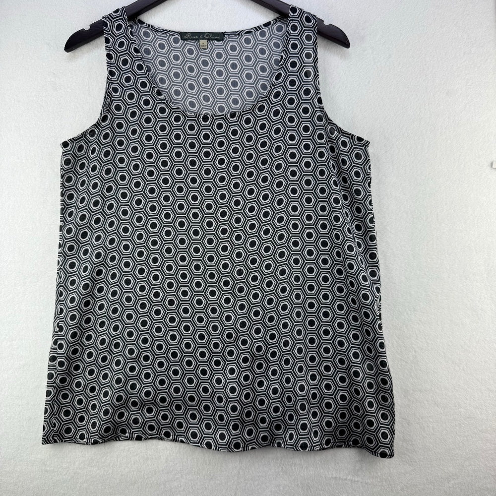 A sleeveless black tank top with a white geometric hexagon pattern, hanging on a black hanger against a light gray textured wall.