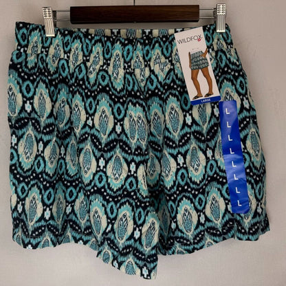 Wildfox brand patterned shorts in a teal, black, and white ikat design, hanging on a wooden hanger with retail tags attached.