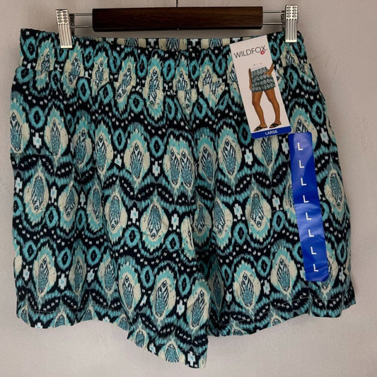 Wildfox brand patterned shorts in a teal, black, and white ikat design, hanging on a wooden hanger with retail tags attached.