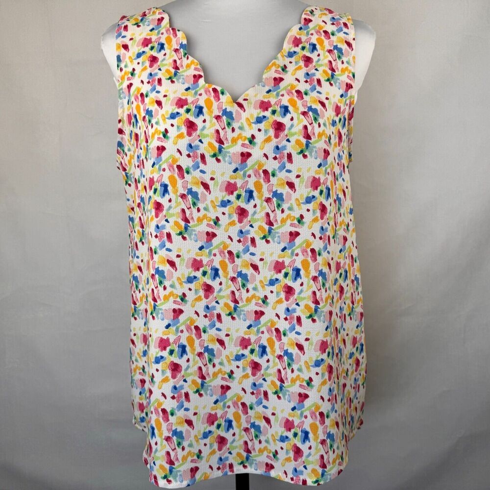 A sleeveless white top with a colorful abstract watercolor print, displayed on a mannequin torso against a neutral gray background.