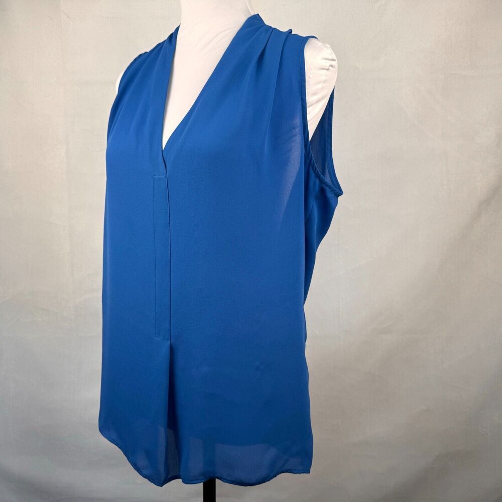 A sleeveless blue V-neck blouse displayed on a white mannequin torso against a light gray fabric backdrop.